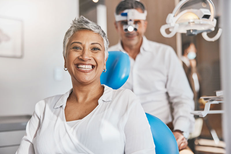 patient happy after she received a teeth cleaning from her dentist with the doctor behind her